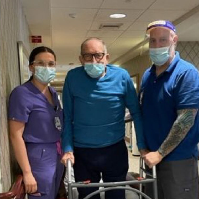 staff helping a patient with a walker