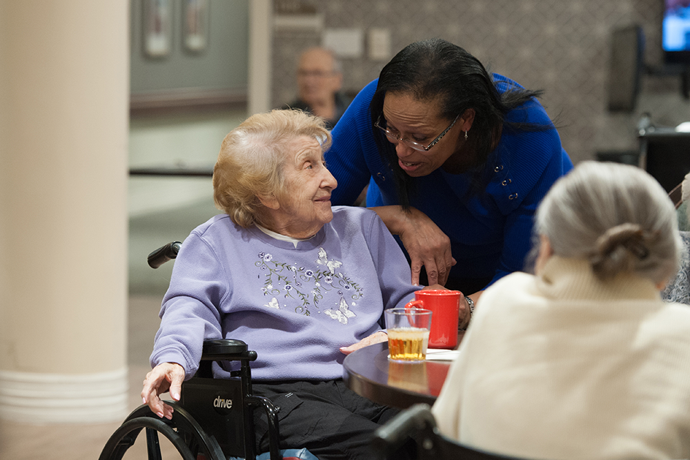 a nurse talking to a resident in a wheel chair