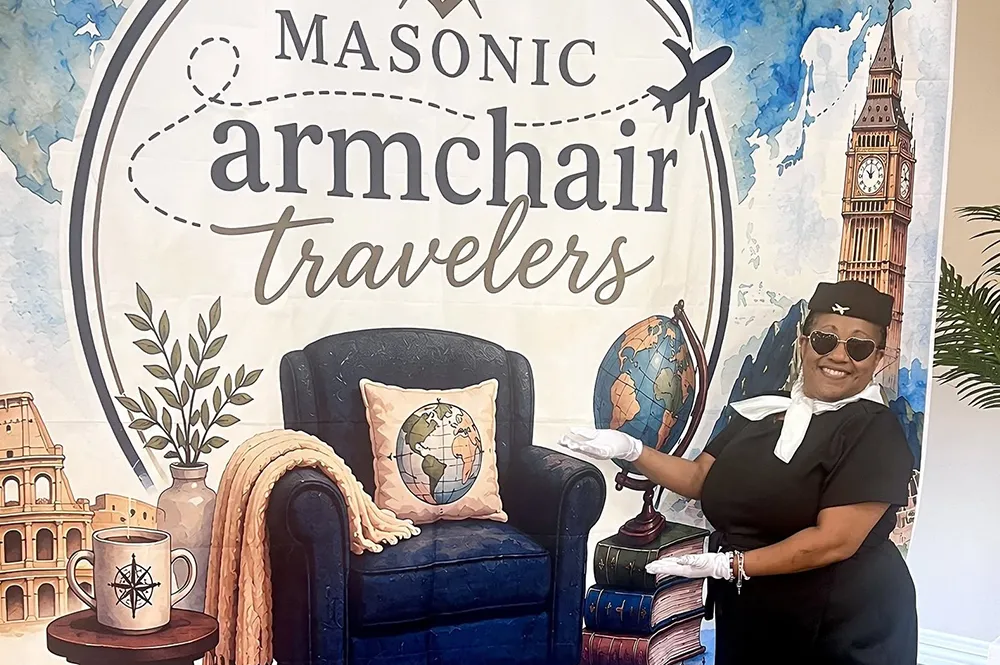 Woman dressed as a flight attendant in front of a Armchair Travelers sign